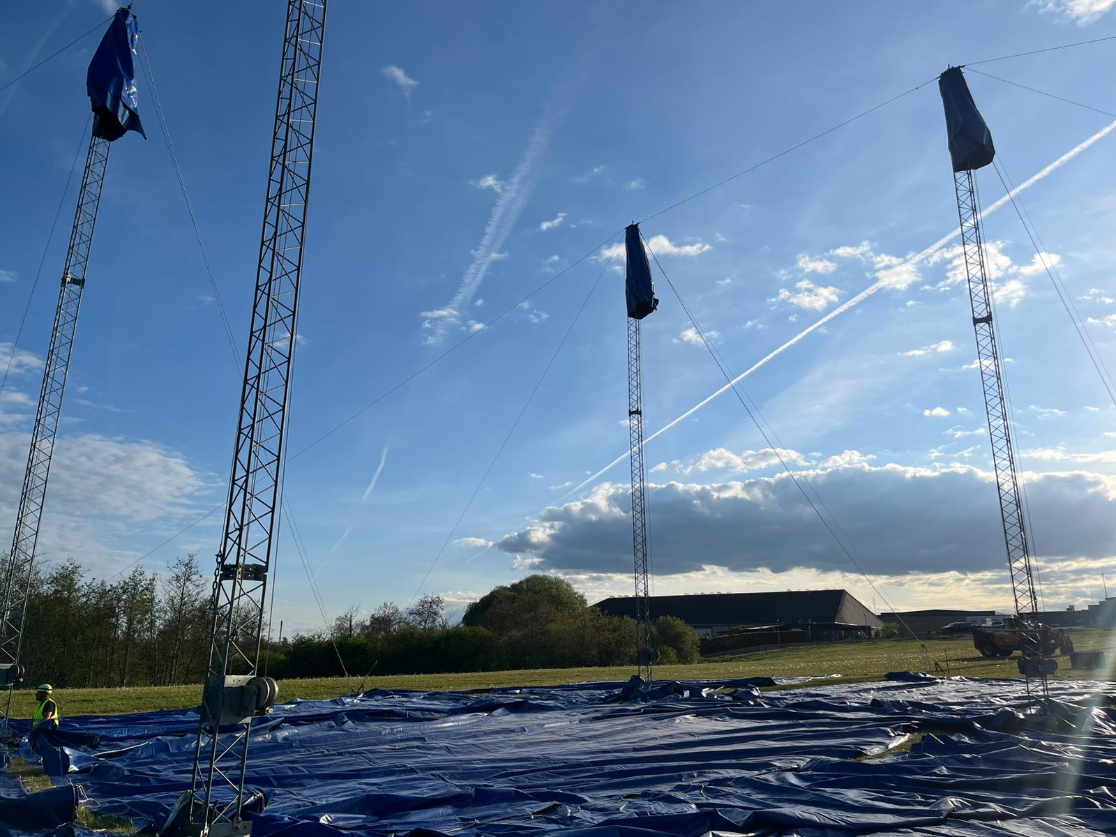 Master-stänger pekar mot blå himmel med duk på marken
